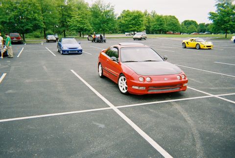 1991 Ford Probe - A red coupe with a black hood is parked in a lot with other vehicles.