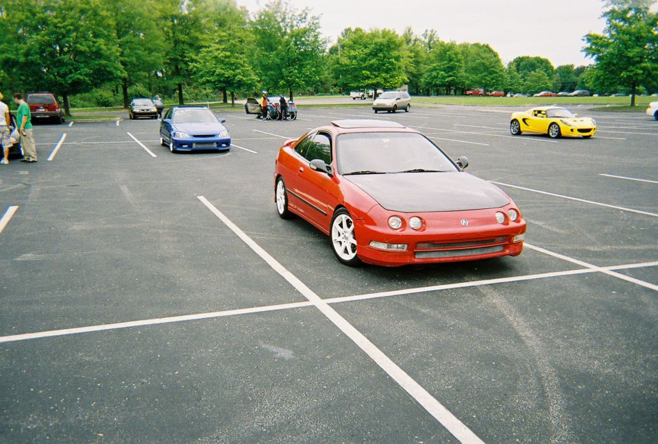 Red coupe with black hood parked in a lot