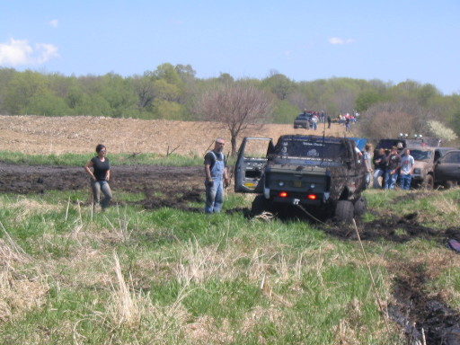 muddy trucks stuck in field, people watching