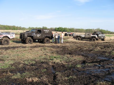 1977 Ford F-150 - Several off-road vehicles are covered in mud during an outdoor event.