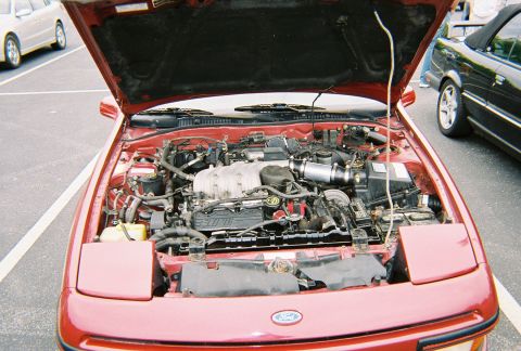 1991 Ford Probe - The engine bay of a 1991 Ford Probe is open, revealing its V6 engine and other components.