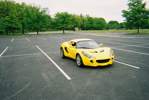 1991 Ford Probe - Yellow sports car parked in an empty lot with trees in the background.