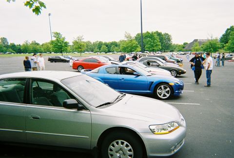 1991 Ford Probe - A gathering of cars and people in a parking lot on an overcast day.
