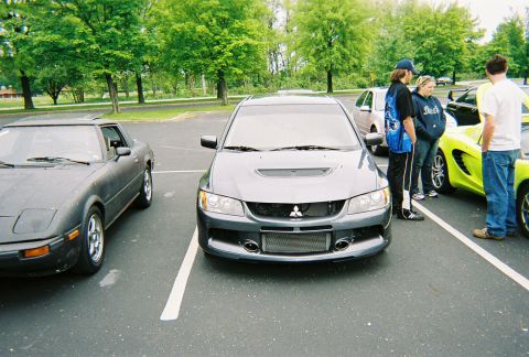 1991 Ford Probe - Several cars and people are gathered in a parking lot on a sunny day.