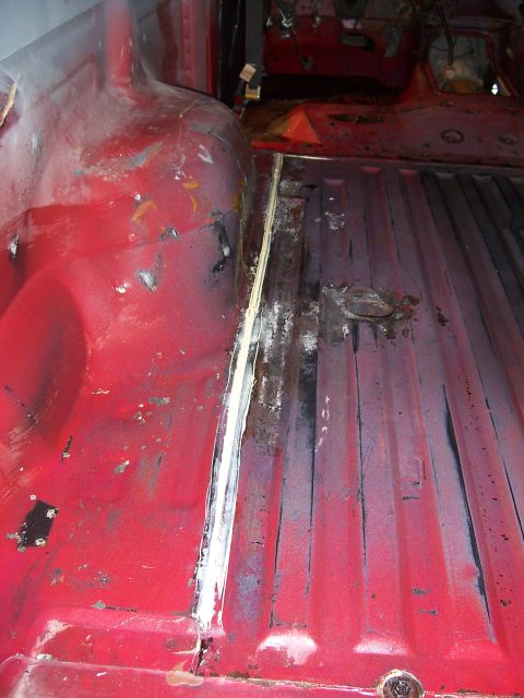 1978 Ford Bronco - The interior floor of a vehicle shows signs of rust and previous repairs, with a prominent seam running down the middle.