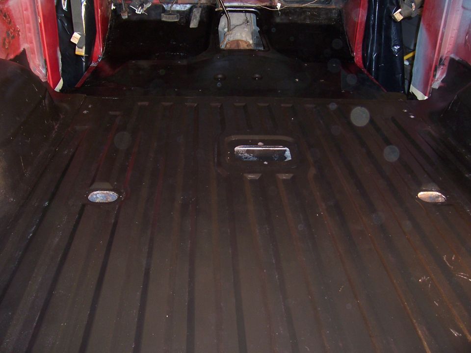 Interior floor of a red vehicle, showing ribbed metal and floor mounts