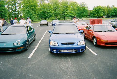 1991 Ford Probe - Several cars are parked in an outdoor lot, including a blue sedan and a red sports car.
