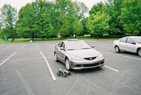 1991 Ford Probe - A silver coupe is parked in a lot next to another car, with a toy monster truck in front of it.