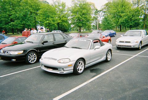 1991 Ford Probe - A silver convertible sports car is parked in a lot alongside other vehicles, with trees in the background.