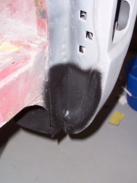 1978 Ford Bronco - Close-up of a vehicle's body panel undergoing repair, showing primer and black undercoating.