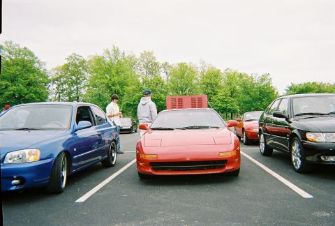 1991 Ford Probe - A red sports car is parked in a lot with other vehicles and trees in the background.