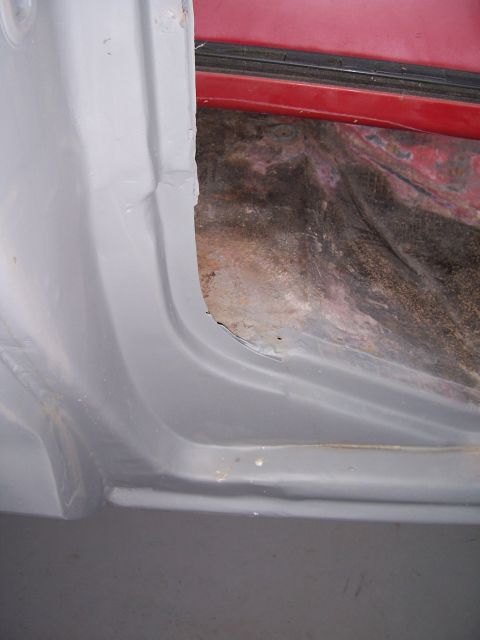 1978 Ford Bronco - Close-up view of the interior door jamb, showing signs of rust and the underlying red paint.