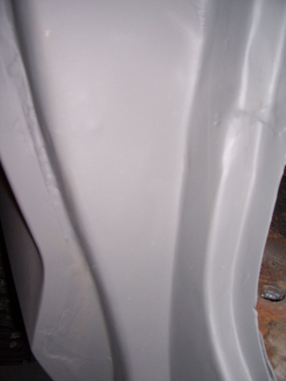 Gray painted metal panel with curved indentations and a visible seam
