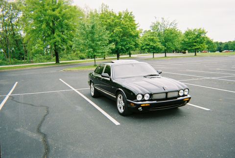 1991 Ford Probe - This black Jaguar XJ is parked in an empty lot, showing its distinctive front grille and headlights.