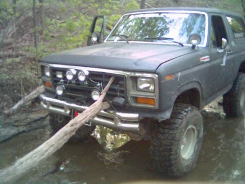 1986 Ford Bronco - 1986 Ford Bronco stuck in mud with a log lodged in its grille.