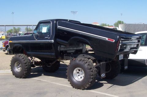 1994 Ford F-150 - This lifted black pickup truck, likely a 1979 Ford F-150, features oversized tires and a modified suspension.