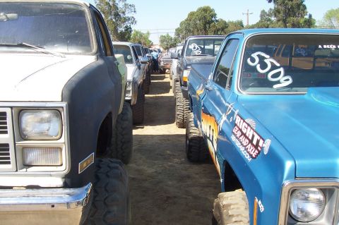 1994 Ford F-150 - Multiple pickup trucks are lined up, some modified for off-road use.
