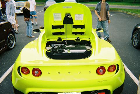 1991 Ford Probe - Lime green Lotus Elise with its rear hood open, parked in a lot with other vehicles.