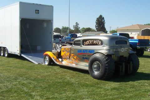1994 Ford F-150 - A custom hot rod truck with flame graphics and 'Undertaker' lettering is parked next to an open trailer.