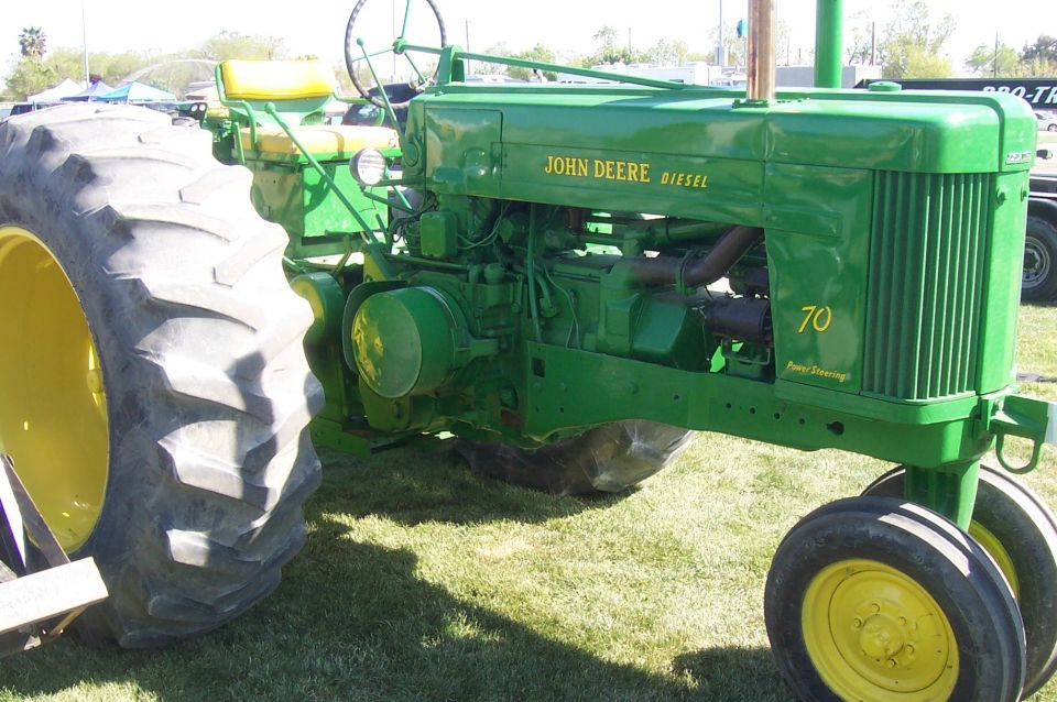 Green John Deere tractor with yellow wheels and seat, showing '70' on the side