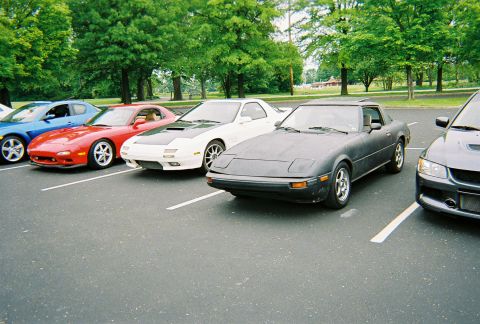 1991 Ford Probe - Several sports cars are parked in a lot, including a dark gray Mazda RX-7 in the foreground.