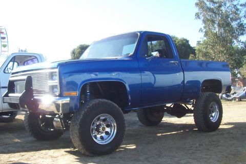 1994 Ford F-150 - A blue pickup truck with a lifted suspension and large tires is parked outdoors.