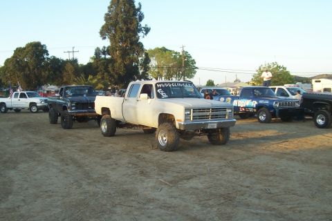 1994 Ford F-150 - Multiple lifted pickup trucks are parked together in an outdoor lot.