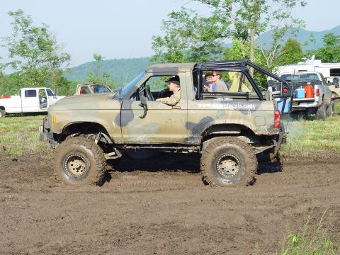 1996 Ford Bronco - This off-road SUV, possibly a Ford Bronco, is stuck in the mud during an event. Another truck is visible in the background.