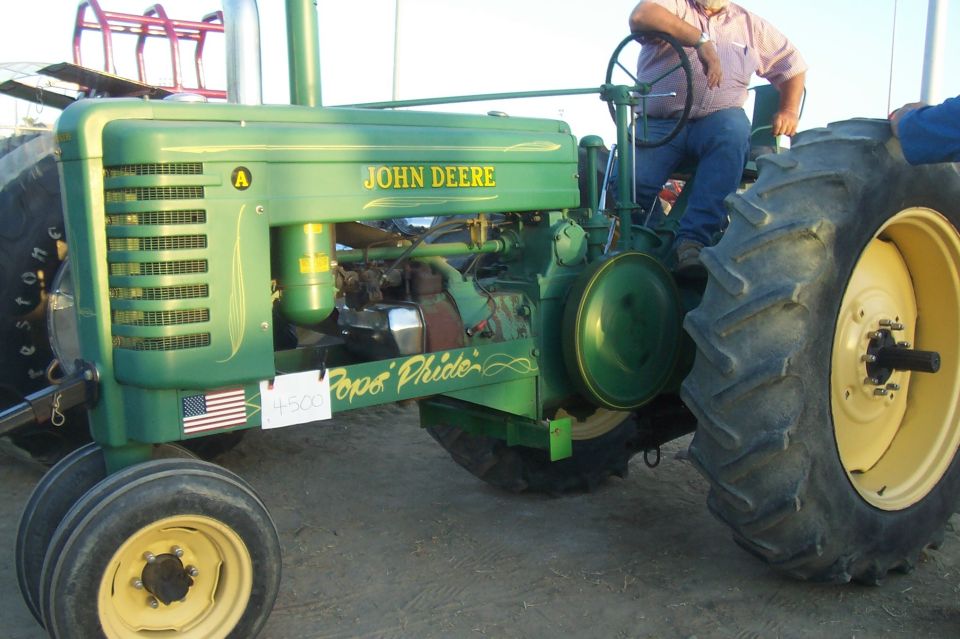 Green John Deere tractor with yellow wheels and "Pope's Pride" painted on the side