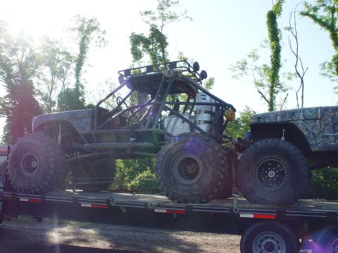 1996 Ford Bronco - Two off-road vehicles, a custom buggy and a Jeep, are transported on a flatbed trailer.