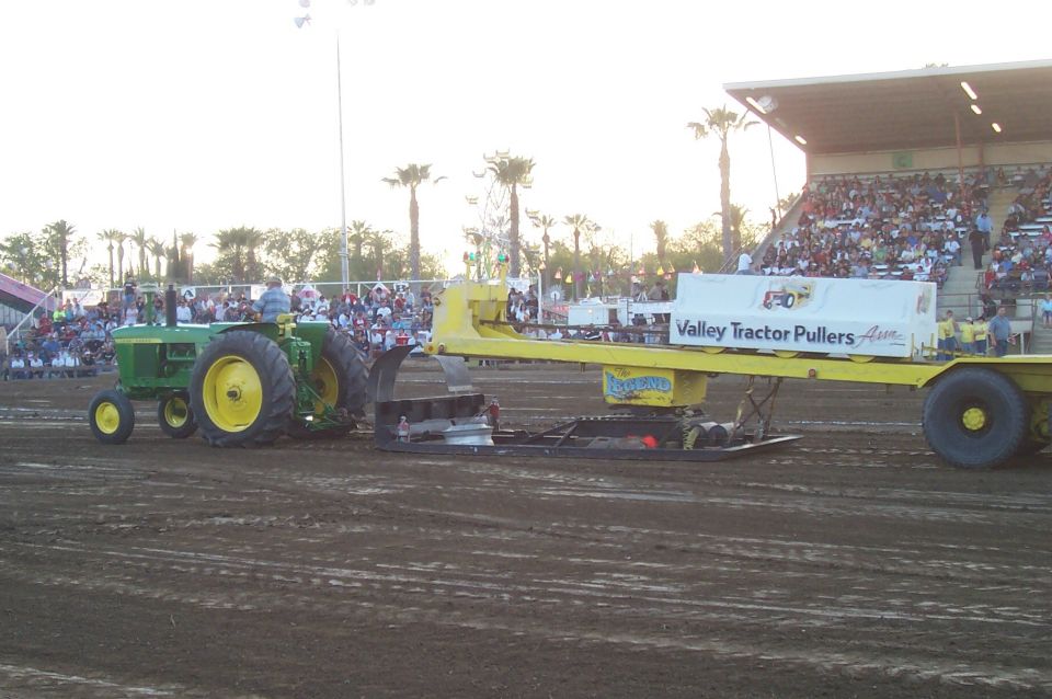 Green tractor pulling weighted sled at tractor pull event