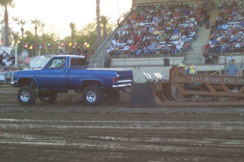 1994 Ford F-150 - Blue pickup truck competes in a tractor pull event with a sled and spectators in the background.
