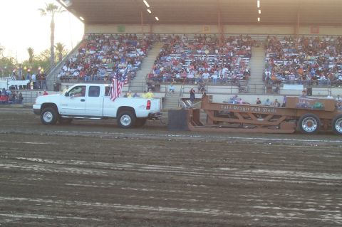 1994 Ford F-150 - A white pickup truck pulls a sled during an event, with spectators in the grandstands watching.