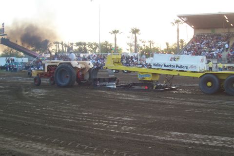 1994 Ford F-150 - A tractor is engaged in a pull competition, with a sled attached and a crowd watching from the stands.