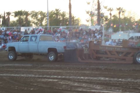 1994 Ford F-150 - A light blue crew cab pickup truck pulls a sled during an event, with spectators in the background.