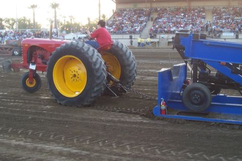 1994 Ford F-150 - Tractor pull event with a red tractor and a blue sled in action.