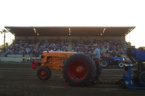 1994 Ford F-150 - A tractor competes in a pull event in front of a large crowd in the stands.