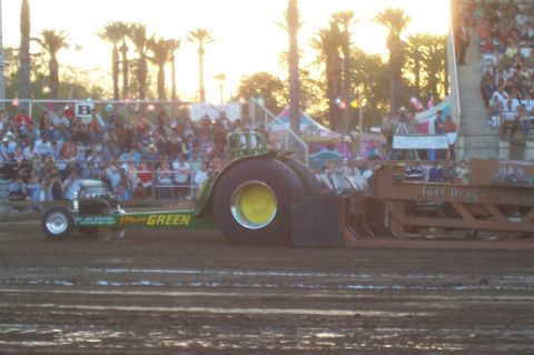 1994 Ford F-150 - A green tractor puller competes in a drag race event with spectators in the background.