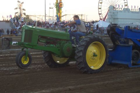 1994 Ford F-150 - A tractor pulls a sled at an outdoor event, with a Ferris wheel and carnival rides visible in the background.