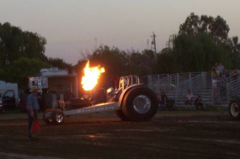 1994 Ford F-150 - A dragster emits a large flame from its exhaust during an event, with spectators in the background.
