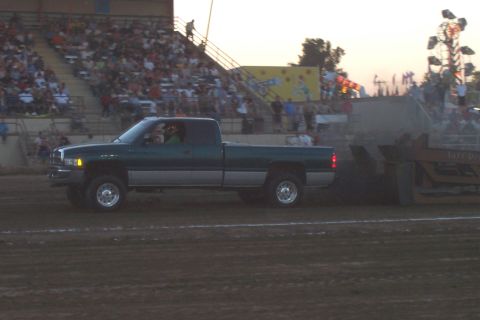 1994 Ford F-150 - A Dodge Ram pickup truck competes in a sled pull event with spectators watching from the stands.