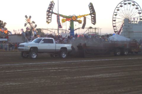 1994 Ford F-150 - A 1994 Ford F-150 pickup truck competes in a pull event at a fairground, with amusement rides in the background.