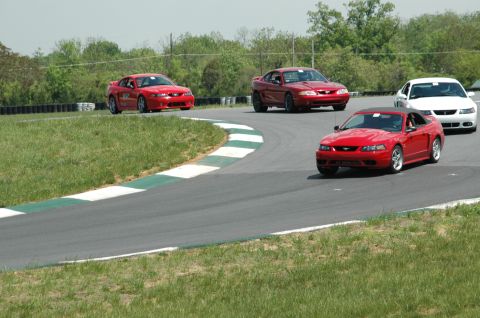 1993 Ford Mustang - Multiple Ford Mustangs participate in a track day event on a sunny afternoon.