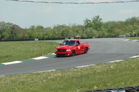 1993 Ford Mustang - A red Ford SVT Lightning pickup truck navigates a turn on a race track.