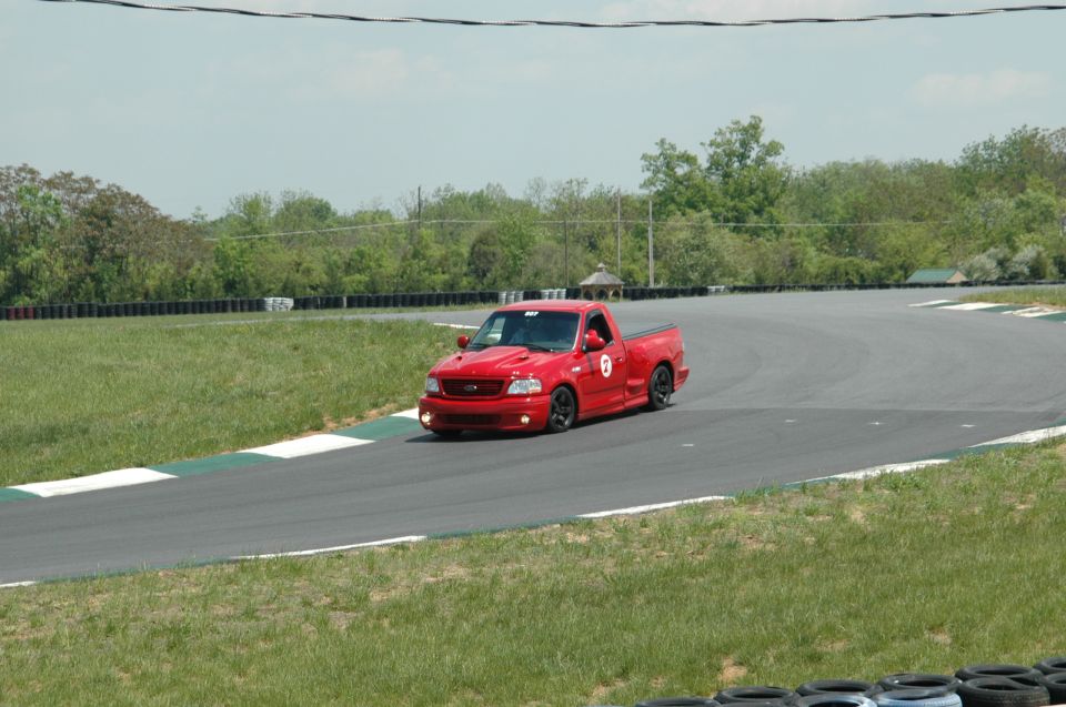 Red 1999 Ford SVT Lightning pickup truck on a race track, front 3/4 view