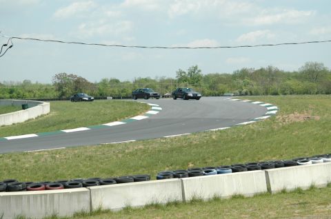 1993 Ford Mustang - Multiple cars are seen on a race track during a sunny day with a cloudy sky.