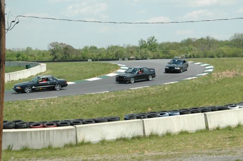 1993 Ford Mustang - Three cars, including a 1993 Ford Mustang, race on a track with grassy verges.
