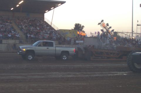 1994 Ford F-150 - A Dodge Ram pickup truck competes in a pull event, with spectators watching from the grandstands.