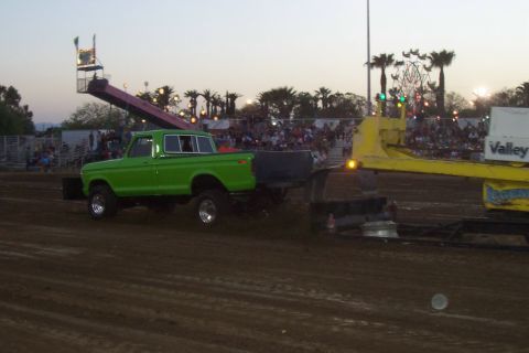 1994 Ford F-150 - A green pickup truck pulls a trailer at an outdoor event with spectators in the background.