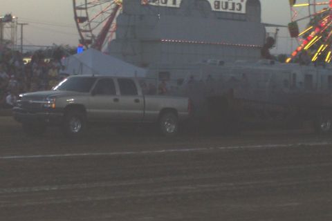 1994 Ford F-150 - A silver pickup truck is seen at a fairground with a Ferris wheel in the background.